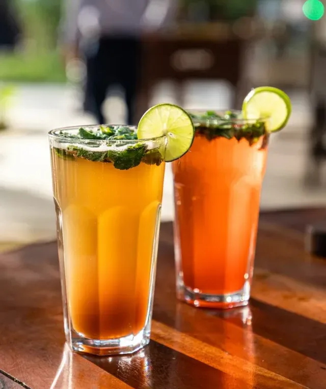 clear drinking glass with brown liquid and sliced lime