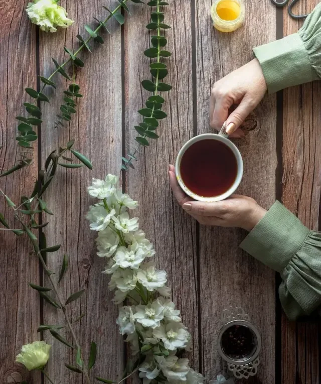 person holding white ceramic mug with detox tea