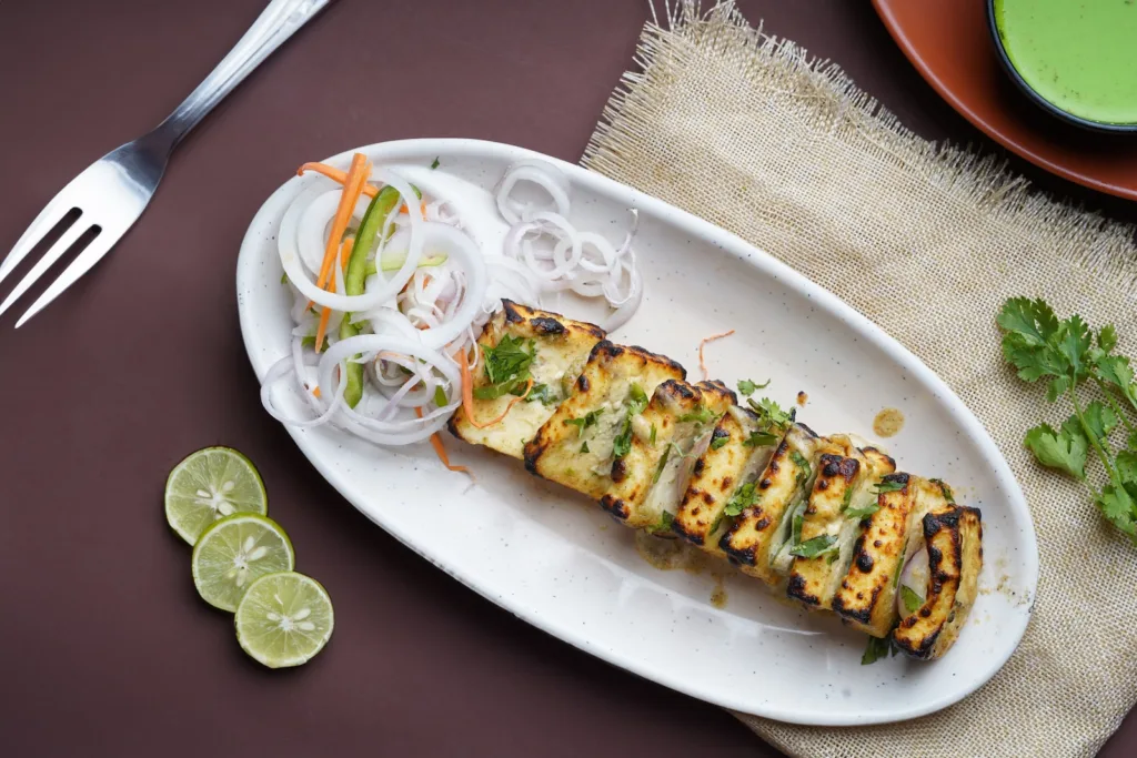a white plate topped with paneer next to a fork
